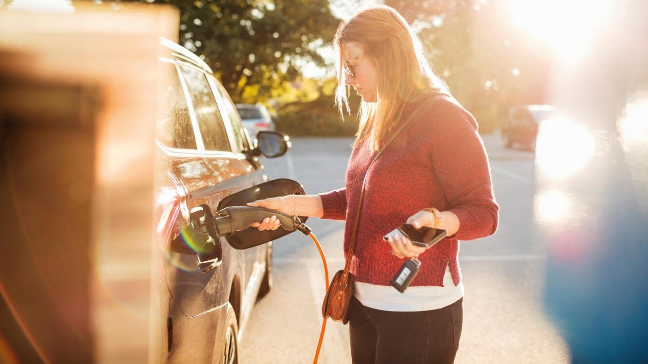 Frau lädt Eauto an öffentlicher Ladestation
